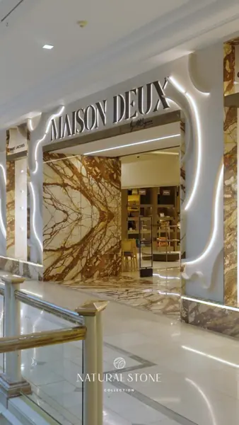 Luminous golden stone is used for the showroom interior, alongside warm metallic details and carefully placed lighting.
