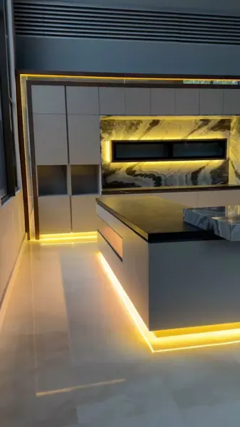 Black marble with white veining is used for the fireplace surround, alongside a golden glow and contrasting dark finishes.
