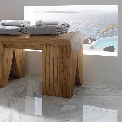 Light marble is used for the floor throughout the room, alongside neatly folded towels and warm natural accessories.