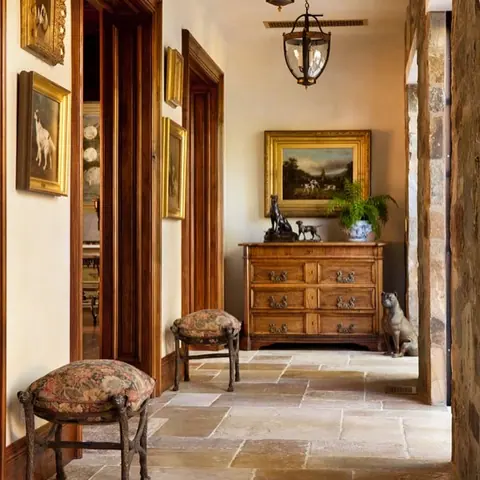 Rustic stone with natural variation is used for the corridor floor, alongside artwork and sculptural furniture.
