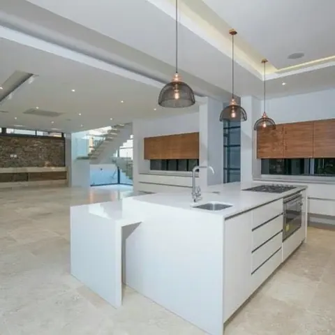 White marble with grey veining is used for the kitchen island and work surfaces, alongside pendant lights and simple cabinetry.
